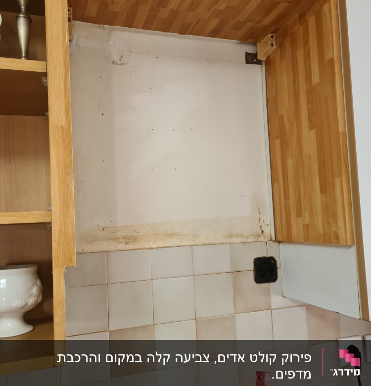 ארון מטבח פתוח עם קיר מלוכלך ושקע חשמל
